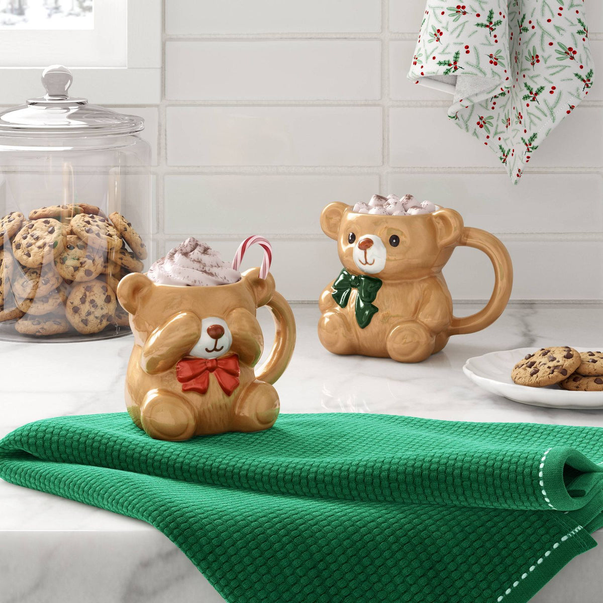 Mini taza de oso Wondershop con moño rojo, crema batida y bastón de caramelo junto a otra taza navideña #tamaño_222 ml / 7.5 fl oz