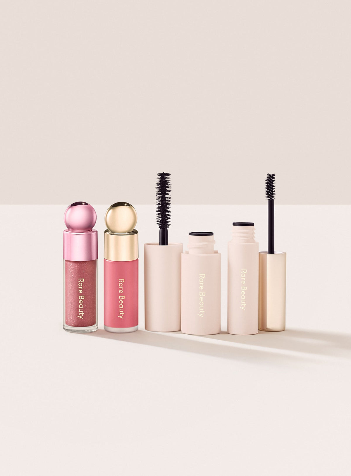 Rubor Happy y gloss Glimmer de Rare Beauty junto a los cepillos de la máscara Black y el gel transparente para cejas