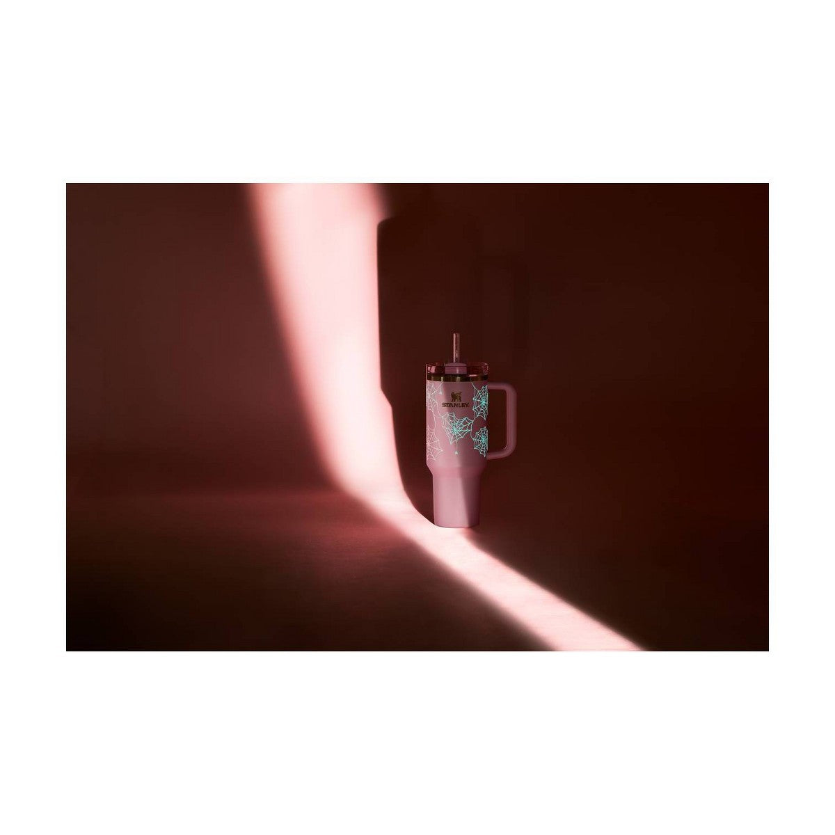 Termo Stanley Pink Sugar Spider Webs con telarañas luminosas en una escena de luz y sombra