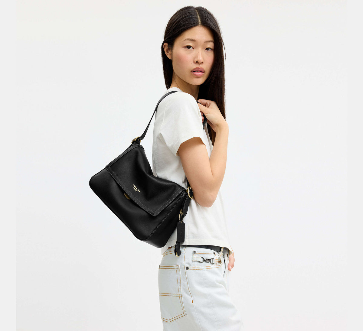 Detalle de Coach Etta Flap Bag negra con cierre y herrajes dorados #color_CA Gold/Black