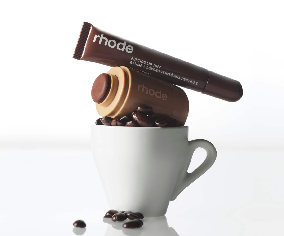 Presentación creativa de Rhode Peptide Lip Tint Espresso y Pocket Blush Toasted Teddy junto a una taza de café #color_Toasted Teddy + Espresso