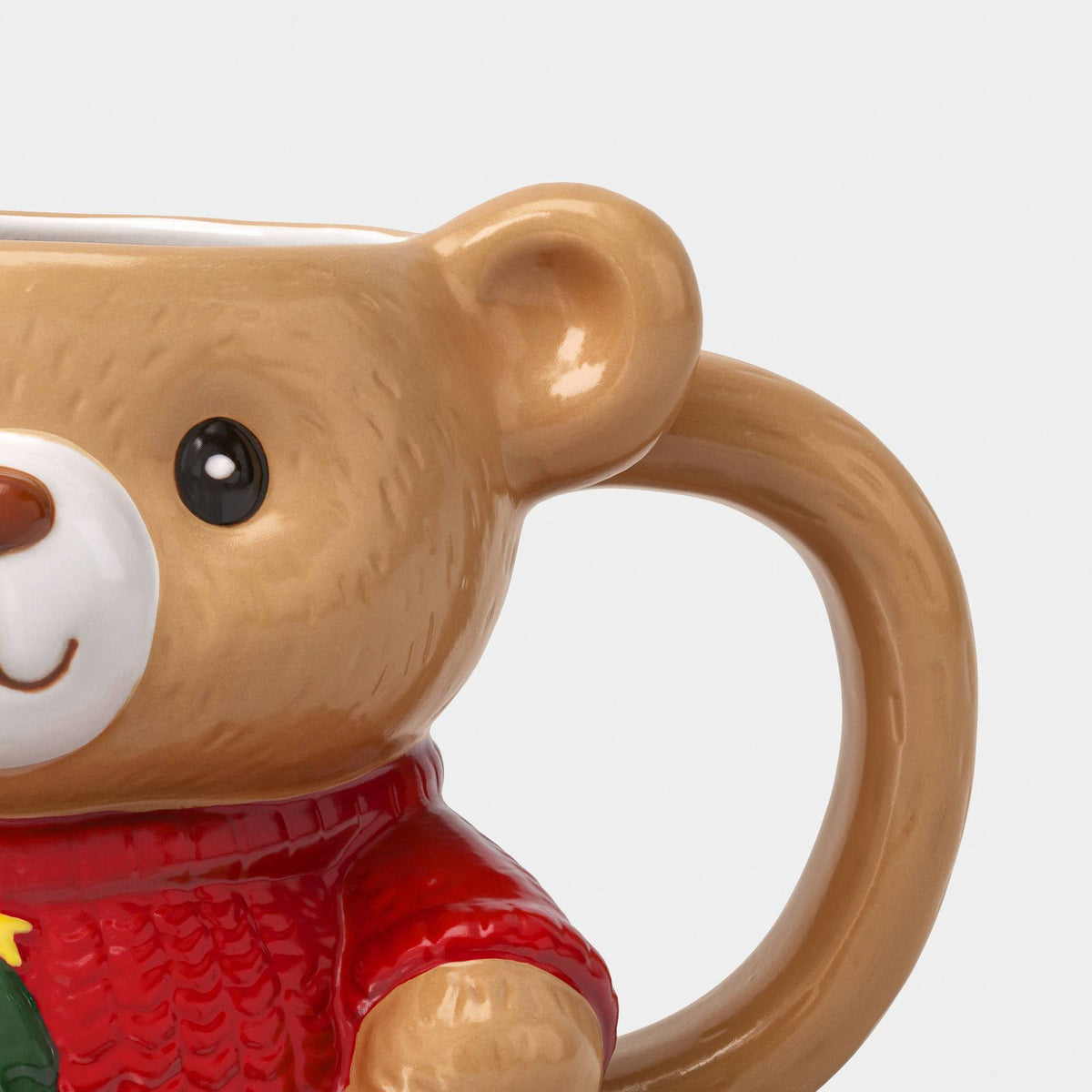 Detalle de taza de oso café Wondershop con hocico blanco, ojos negros y suéter rojo #tamaño_473 ml / 16 fl oz